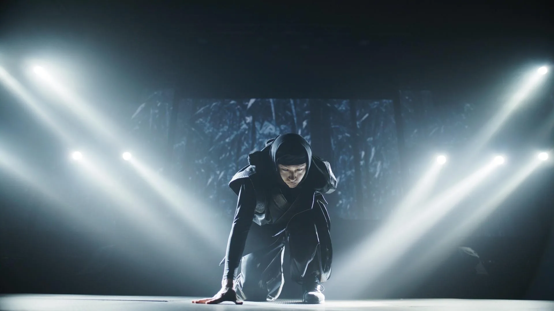 Lone ninja poised in a single spotlight on stage — Ninja + Kabuki Tokyo